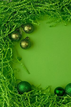 Christmas plain green background with green balls, with a frame of cut corrugated paper and wooden decorationsの写真素材