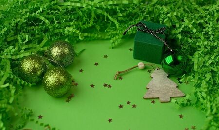 Christmas plain green background with green balls, with a frame of cut corrugated paper and wooden decorationsの写真素材