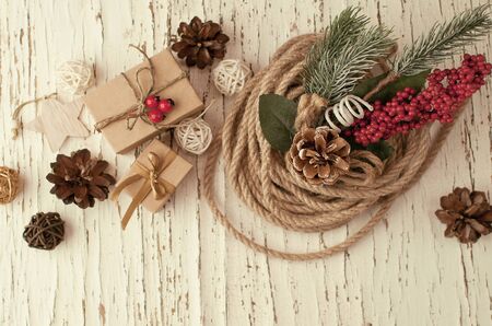Retro Christmas background on old cracked wooden background with peeling white paint with gifts in craft paper, a scourge and wooden decorations for the Christmas tree and a sprig of fir in red berriesの写真素材