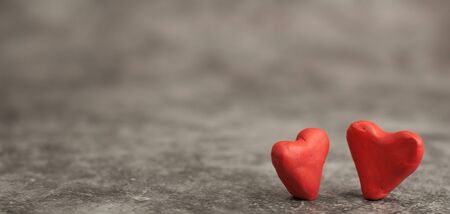 Festive background for Valentine's Day on a gray cement background with hearts in retro style from plasticine. Sachets are a pair of lovers newlyweds in white and pinkの写真素材