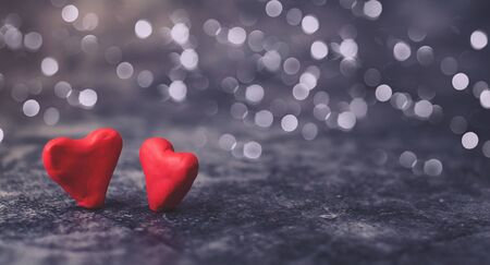 Festive background for Valentine's Day on a gray cement background with hearts in retro style from plasticine. Sachets are a pair of lovers newlyweds in white and pinkの写真素材