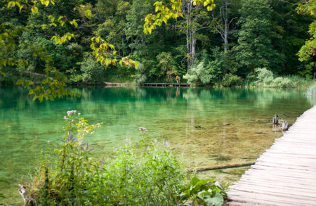 Tourists walking along a hiking path across the lakeの写真素材