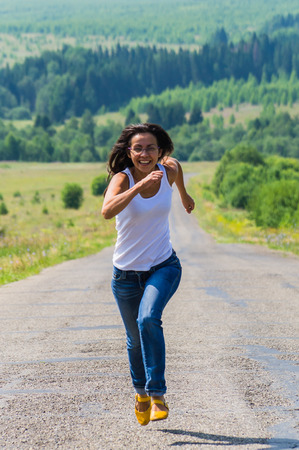 cheerful girl runs along the highway towardsの写真素材