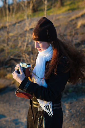 Girl photographer with an old camera taking pictures of the sunset