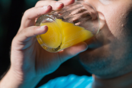 The man is drinking orange juice の写真素材