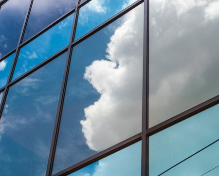 Buildings mirror window with reflection of cloudの写真素材