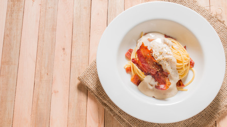 Bacon spaghetti in white plate on wooden background.の写真素材