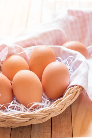 Eggs in a basket on wooden table with ligh from behide.の写真素材