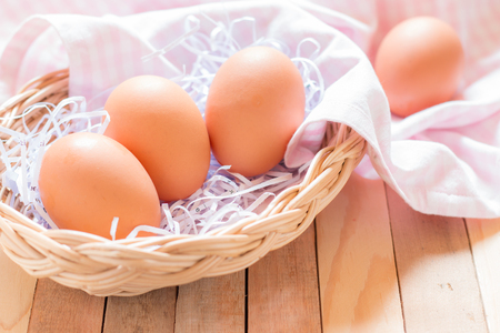 Eggs in a basket on wooden table.の写真素材