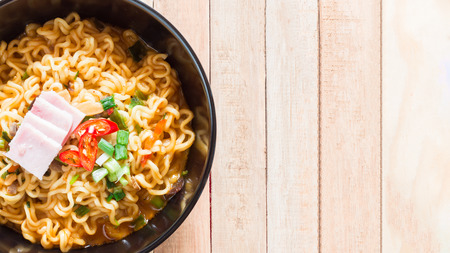 Top view of korean noodles(Ramyun) in black bowl on wooden table.の写真素材