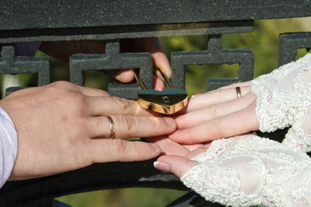 Newlyweds hang up a lock on the fenceの写真素材