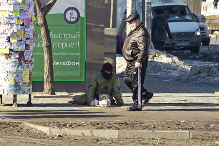 VOLGOGRAD - FEBRUARY 22  A man walks past a sitting on the floor of the poor in need of alms  February 22, 2014 in Volgograd, Russia のeditorial素材