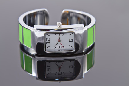 Glamorous women s watch with a green bracelet on a reflecting surface