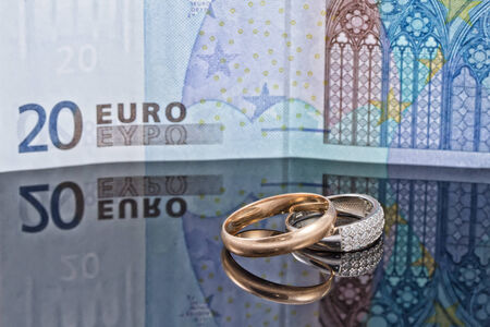 Gold and silver wedding rings on background of 20 Euro banknoteの写真素材
