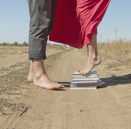 girl stands on a stack of books to reach out and kiss the guyの写真素材