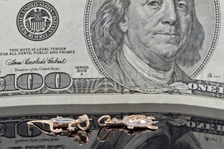 delicate gold charms on the background of hundred dollars billsの写真素材