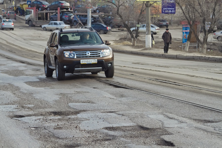 VOLGOGRAD - FEBRUARY 07: Terrible pavement or the lifting bridge. The car has to go around the pit on the road on the tram tracks. February 07, 2015 in Volgograd, Russia.のeditorial素材