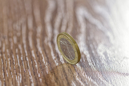one Euro coin rolls on wooden surfaceの写真素材
