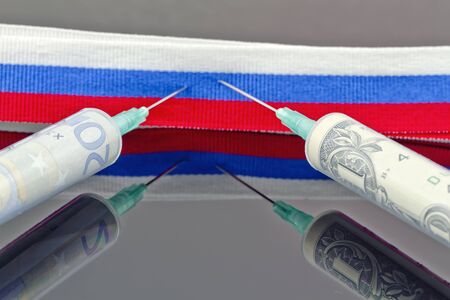 Syringes with dollars and euros pierce the ribbon of the Russian flagの写真素材