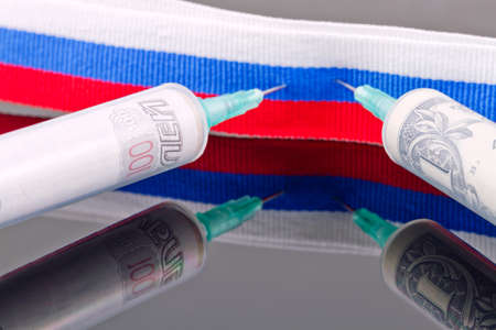 Syringes with dollars and roubles pierce the ribbon of the Russian flagの写真素材
