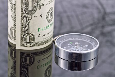 dollar bill and compass are on the surface which reflects mapの写真素材