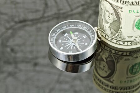 dollar bill and compass are on the surface which reflects mapの写真素材