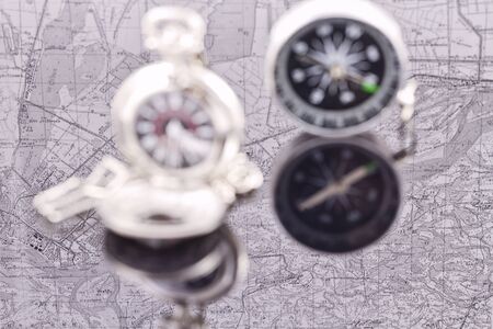 compass and a silver pocket watch on the background reflection mapsの写真素材