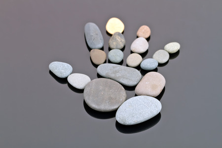 The human palm  is fine going out of small sea stones on the reflecting surfaceの写真素材