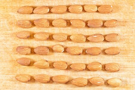 Almonds lie in neat rows on a wooden tableの写真素材