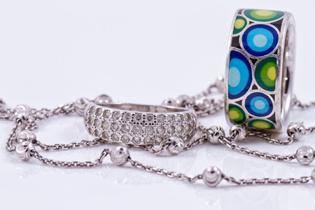 Fine silver rings are together with unusual silver chain on a white acrylic Boardの写真素材