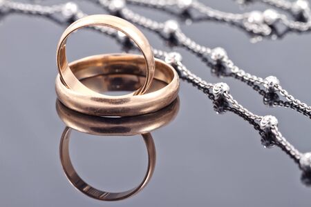 Two Golden wedding rings and elegant silver chainの写真素材