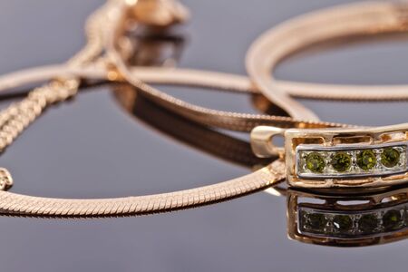 Beautiful and elegant gold earrings with emeralds against other gold jewelryの写真素材