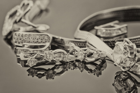 gold ring, earrings and chains on a reflective surfaceの写真素材