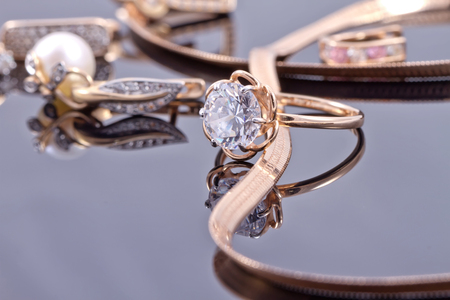 gold ring, earrings and chains on a reflective surfaceの写真素材