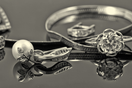 gold ring, earrings and chains on a reflective surfaceの写真素材