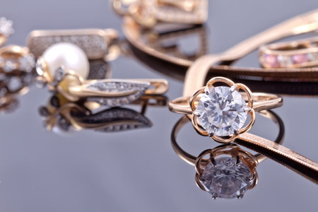 gold ring, earrings and chains on a reflective surfaceの写真素材