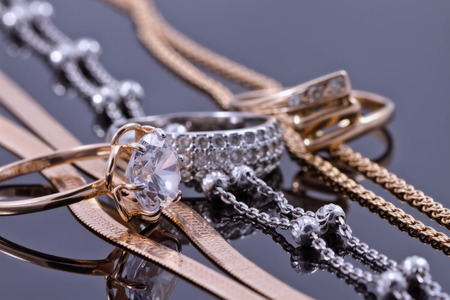 gold ring, earrings and chains on a reflective surfaceの写真素材