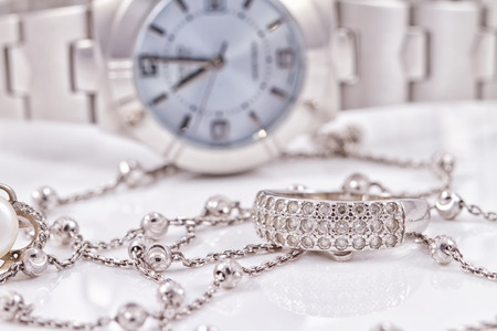 Silver ring and chain on the background of women's watchesの写真素材