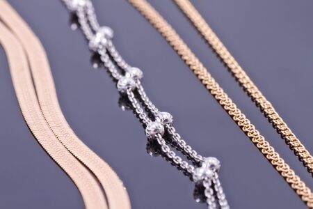 Silver and gold chains of different weaving lie next to each otherの写真素材