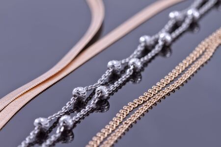 Silver and gold chains of different weaving lie next to each otherの写真素材