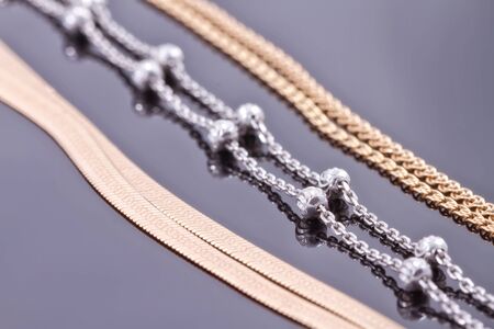 Silver and gold chains of different weaving lie next to each otherの写真素材