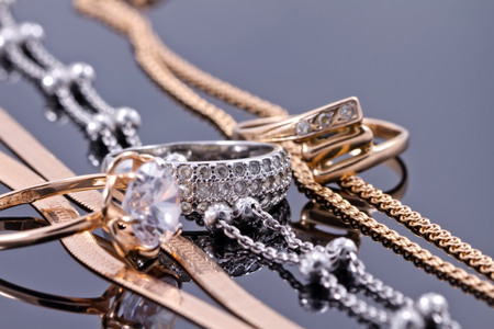 gold ring, earrings and chains on a reflective surfaceの写真素材