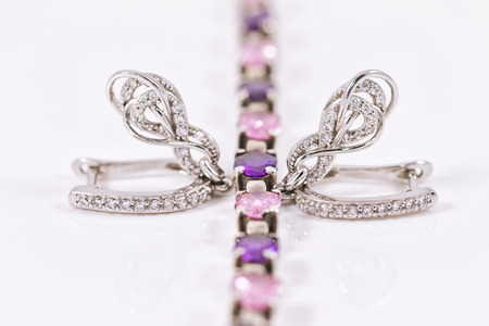elegant silver earrings and a silver bracelet with red and purple crystalsの写真素材