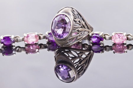 Carved silver ring with a blue gem and a silver bracelet with purple crystalsの写真素材