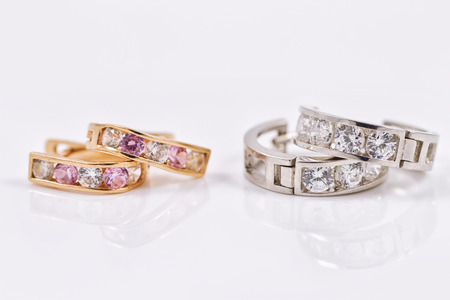 Small neat earrings in gold and silver on the reflecting surfaceの写真素材