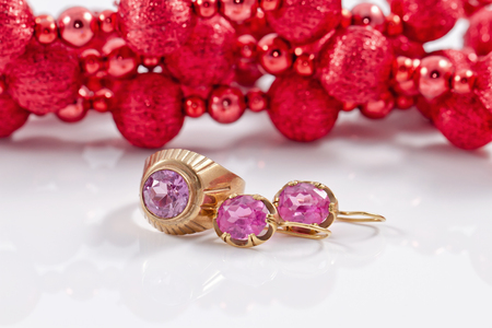 set of gold jewelry of earrings and ring with alexandrite on the background of Christmas decorationsの写真素材