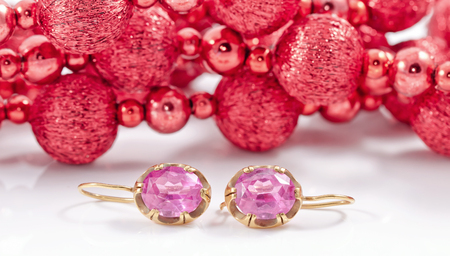 set of gold jewelry of earrings with alexandrite on the background of Christmas decorationsの写真素材