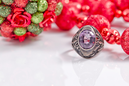 Elegant silver ring with a precious stone on a background of Christmas tree balls and garlandsの写真素材