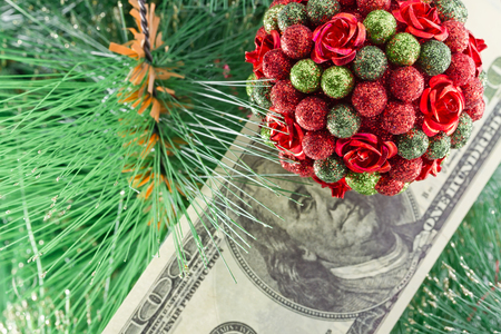 Beautiful Christmas ball in the shape of a bouquet and a hundred dollar bill hanging on the Christmas treeの写真素材