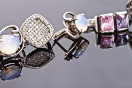 Silver earrings of different sizes and shapes lie in a rowの写真素材